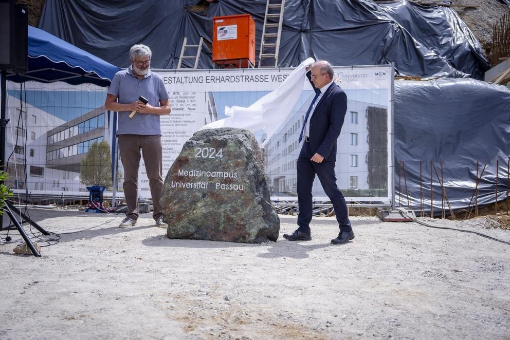 Dr. Rolf-Dieter Jungk, Amtschef im Bayerischen Staatsministerium für Wissenschaft und Kunst (rechts im Bild) enthüllt den Grundstein für den Multimediahörsaal gemeinsam mit dem Vertreter der Bauherren, Rudolf Ramelsberger. Foto: Universität Passau 