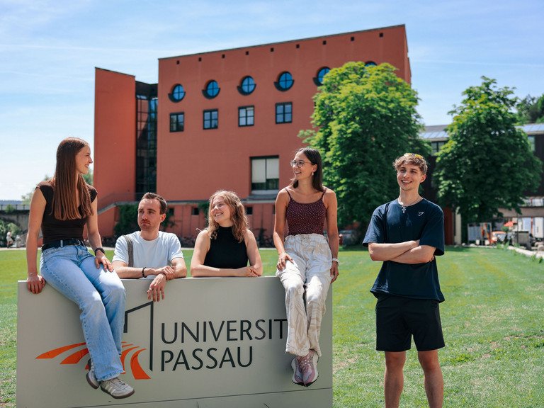 Students in front of the campus logo of the University of Passau. Photo credit: University of Passau