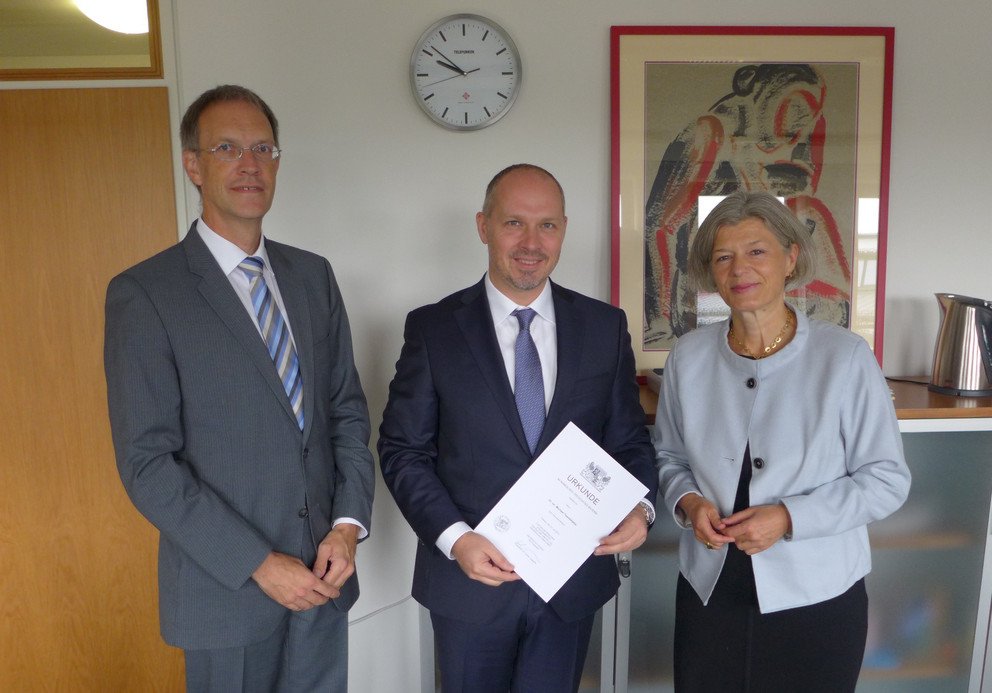 Bildhinweis: Dekan Prof. Dr. Hans-Georg Dederer, Michael Tsambikakis und Pr&auml;sidentin Prof. Dr. Carola Jungwirth bei der &Uuml;bergabe der Ernennungsurkunde. Foto: Universit&auml;t Passau