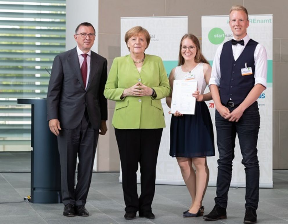 Lisa Knott und Max Borcherding nehmen die Urkunde in Berlin von Kanzlerin Angela Merkel entgegen.